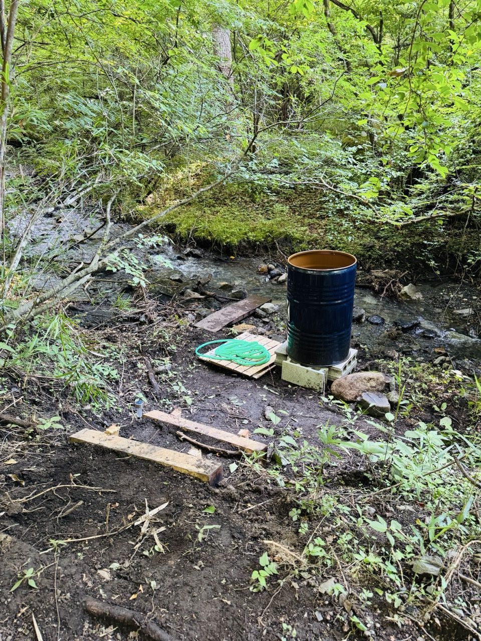 沢のそばでドラム缶風呂を組み上げる様子（湧火・私有地の五右衛門風呂づくり）